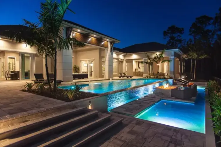 Dusk pool with a sunken fire pit, raised spa and an infinity edge spilling into the water