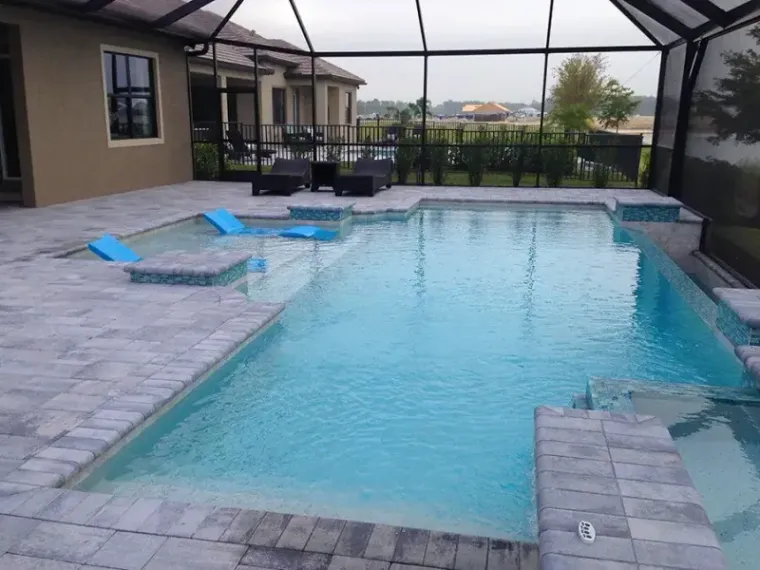 Lakefront screened swimming pool with blue in-pool loungers built by Craig's Pacific Pools