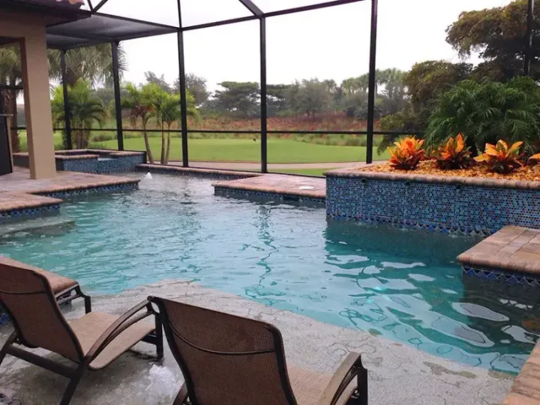 Screened pool with blue glass tile looking out over a golf course