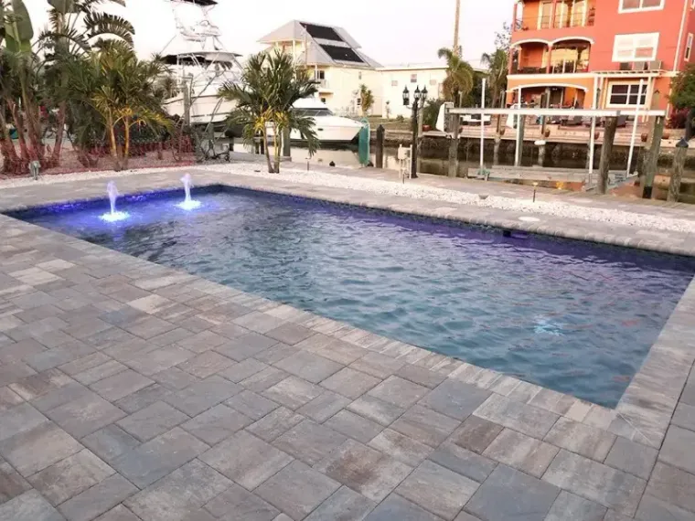 Canal-front Cape Coral pool at dusk with colour-changing fountain jets running